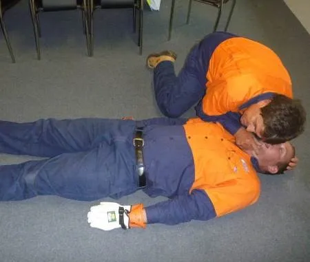 a person in high visibility clothing providing CPR to another for HLTAID009– Provide Cardiopulmonary Resuscitation
