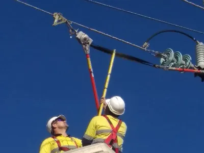 2 people in safety gear using a stick to work on power lines for UETDRDO004- Maintain Energised High Voltage Distribution Overhead Electrical Apparatus (Stick)